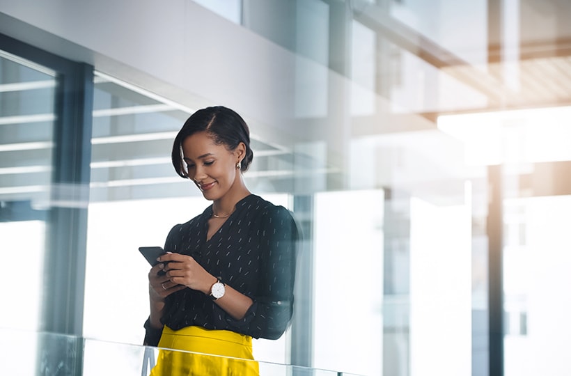 A woman in an office smiling while looking at her phone