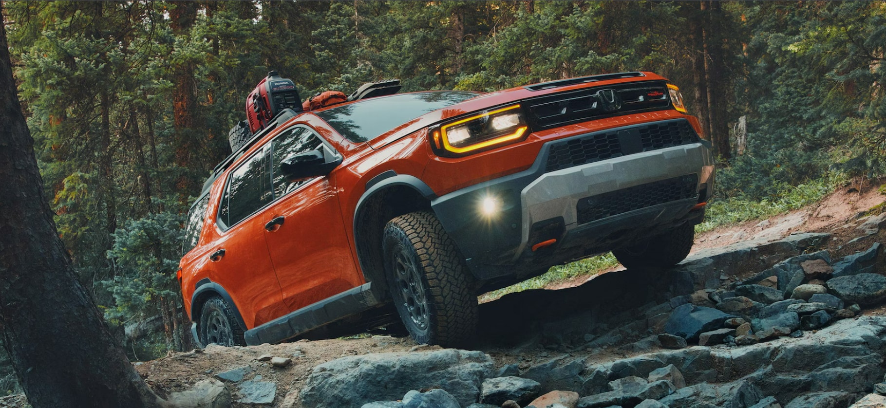 An orange 2026 Honda Passport riding through the forest.