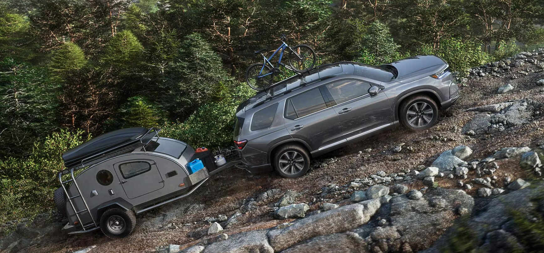 A 2025 Honda Pilot towing a camper up a rocky hill in the mountains.