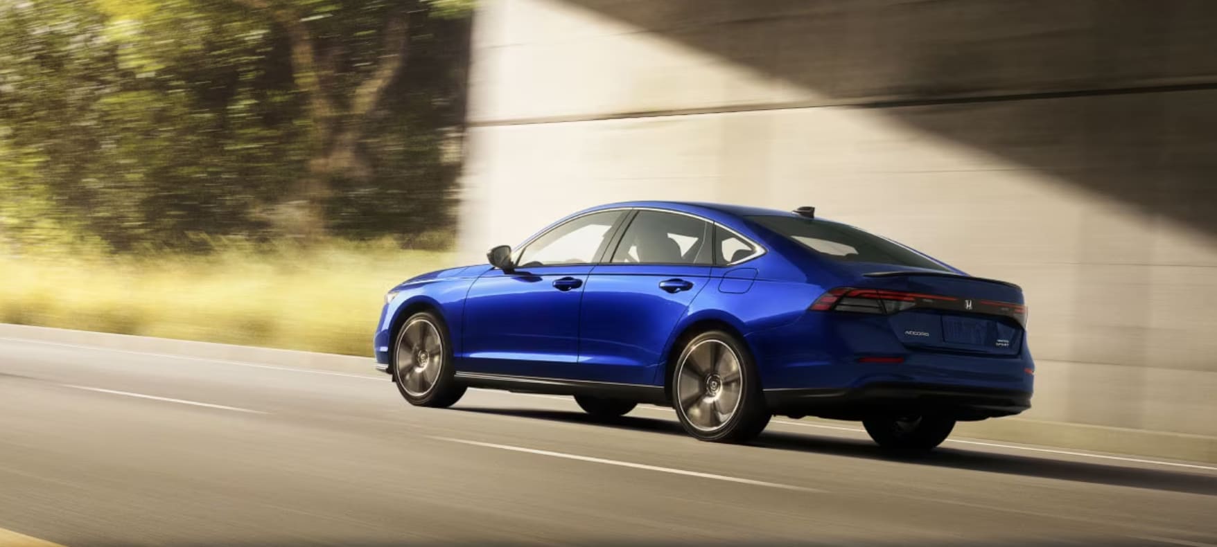 A blue 2023 Honda Accord drives down a road through a tunnel