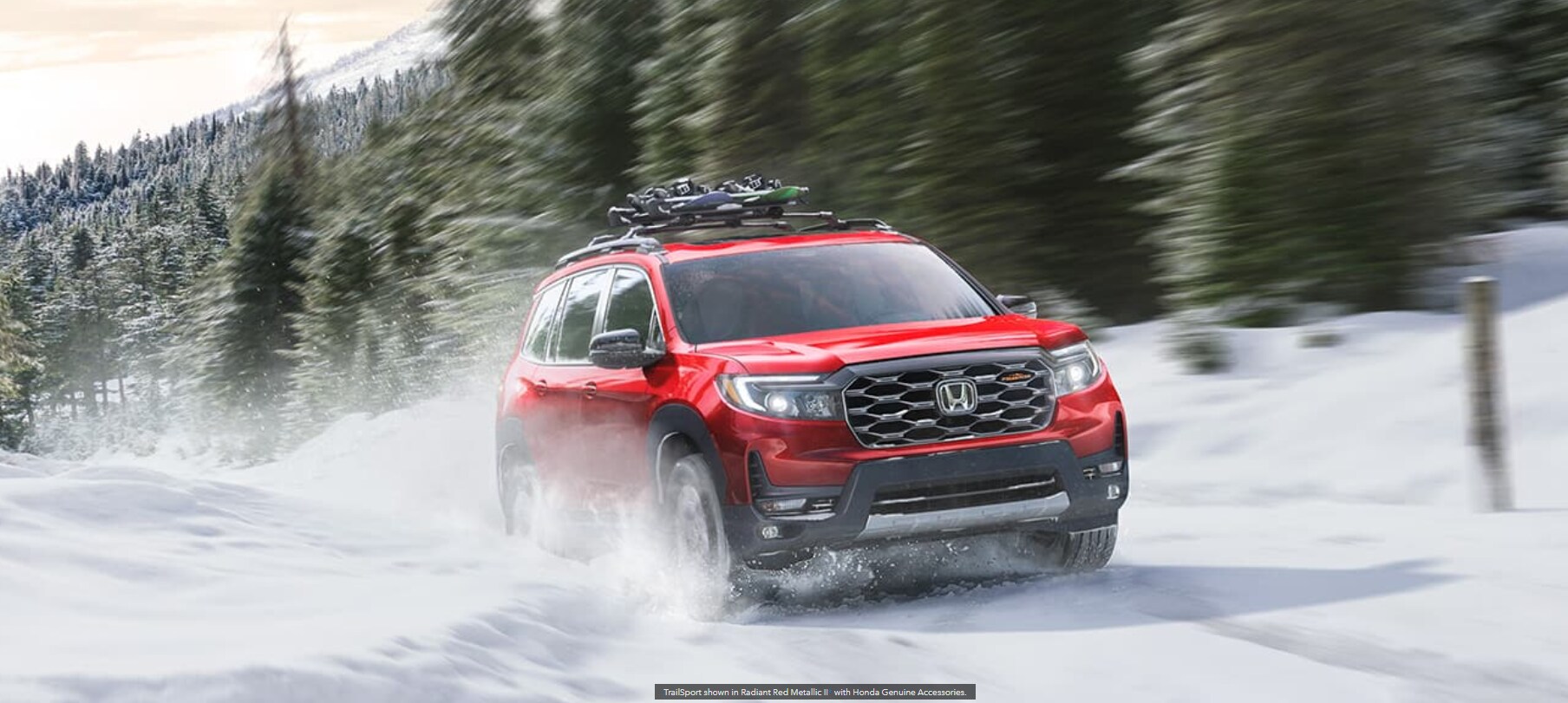 A red 2023 Honda Passport speeds through the snow