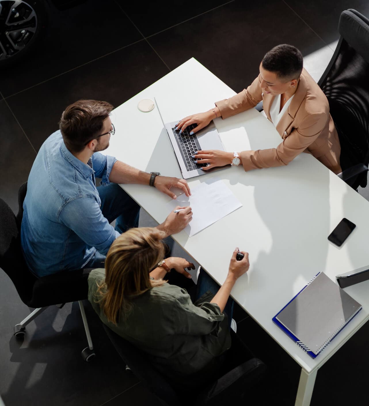 A couple sits at a desk with a dealership finance agent.