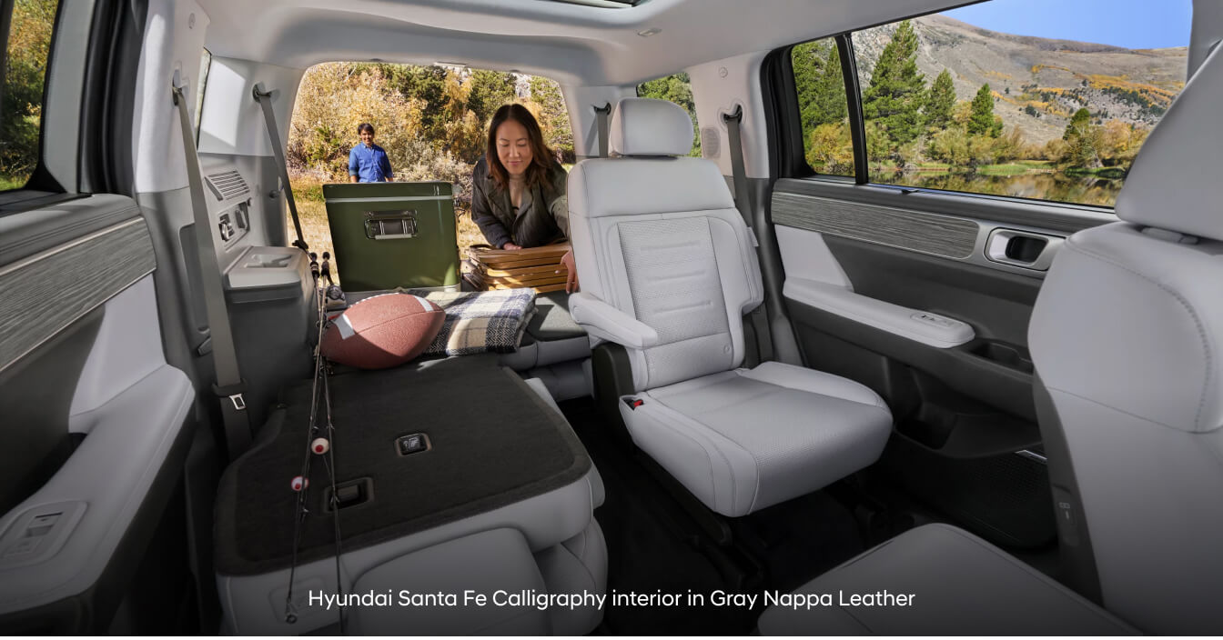 Hyundai Santa Fe Calligraphy in Gray Nappa Leather with folded seats on lakeside campsite.