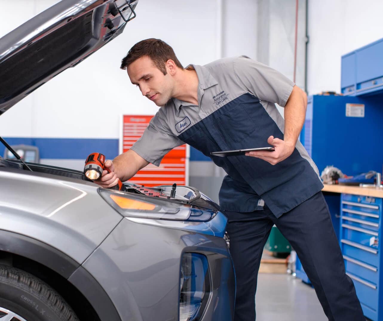 A Hyundai certified tecnician inspects under te hood of a Hyundai car.