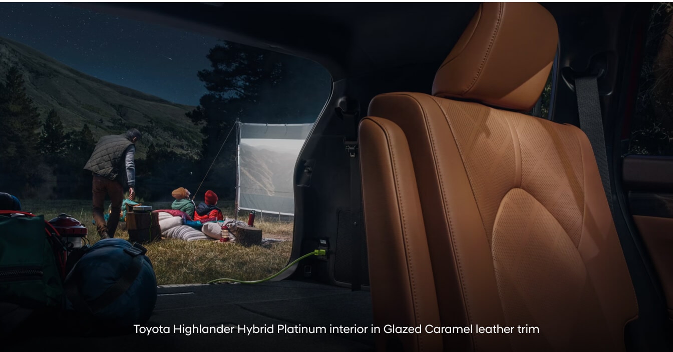 Toyota Highlander Hybrid Platinum in Glazed Caramel Leather with folded third-row seats on mountain campsite.
