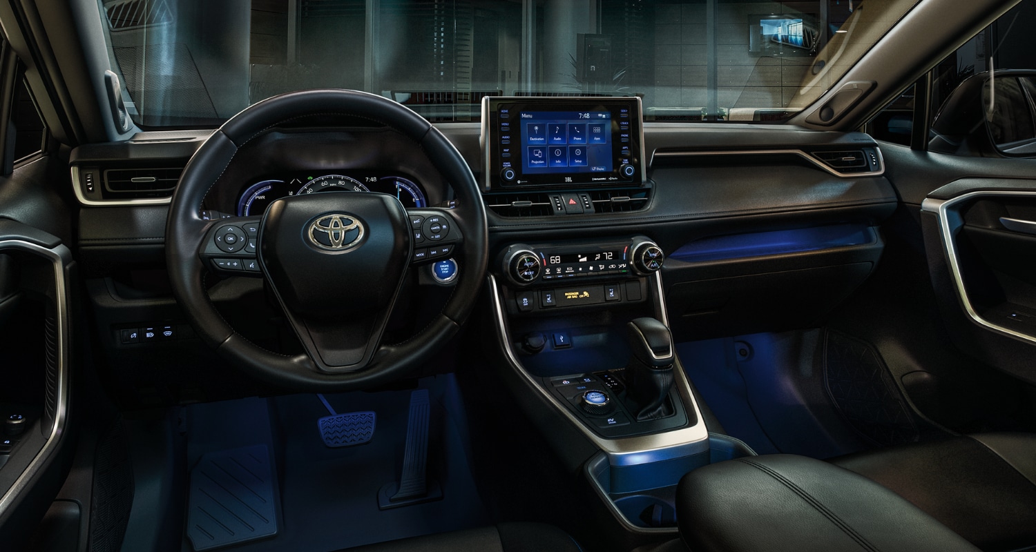 Front interior dashboard and center console area inside the new 2021 Toyota RAV4 Hybrid with blue ambient lighting