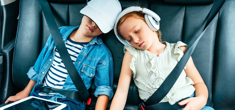 Exhausted children with digital devices sleeping in car during trip