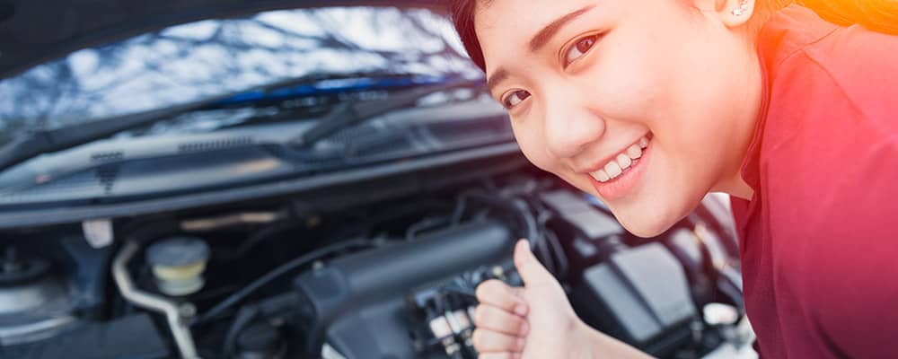Woman smiling after checking for transmission fluid leaks