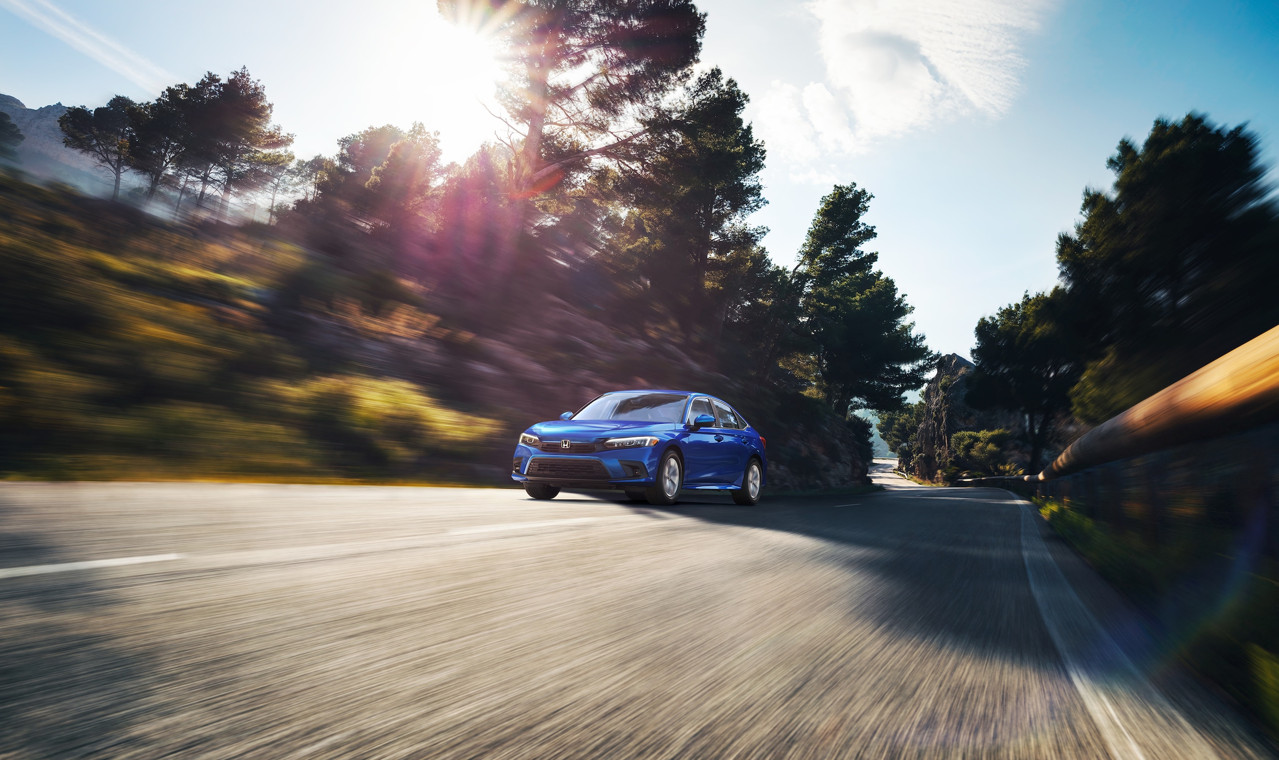 blue Honda Civic LX driving fast down a tree-lined road