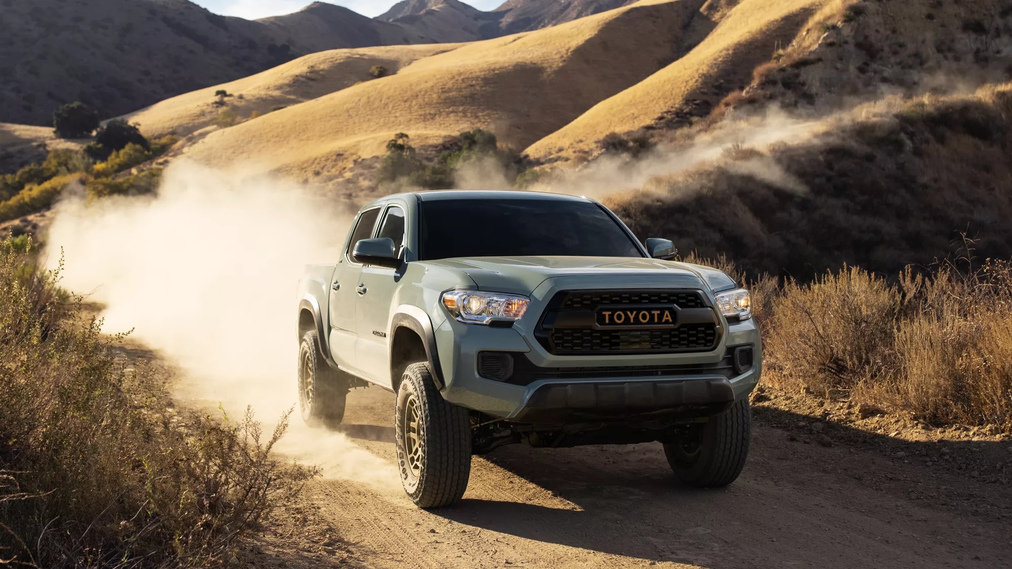 gray Toyota truck driving on a dry, dusty road