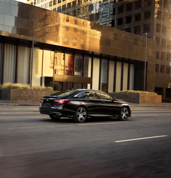 2022-Honda-AccordHybrid-Touring-Sedan.png black Honda Accord Hybrid driving past an office building