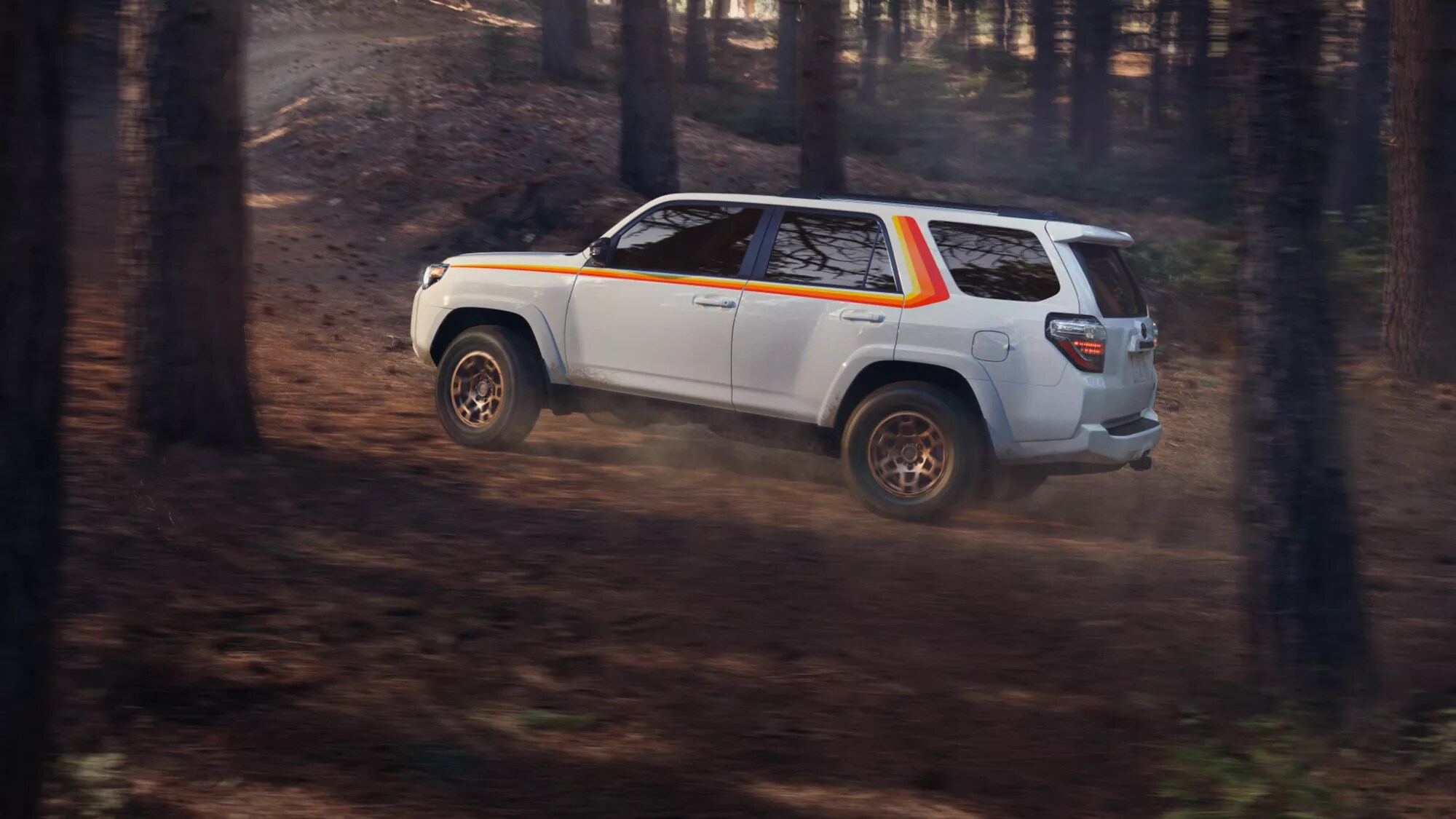 white Toyota SUV driving off-road through the woods
