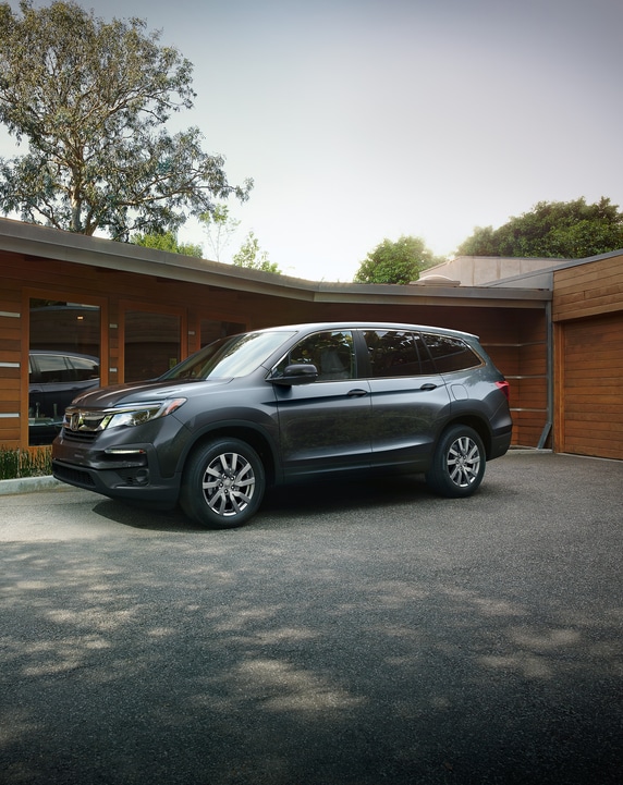 dark gray Honda Pilot SUV parked in front of a modern, wood framed home