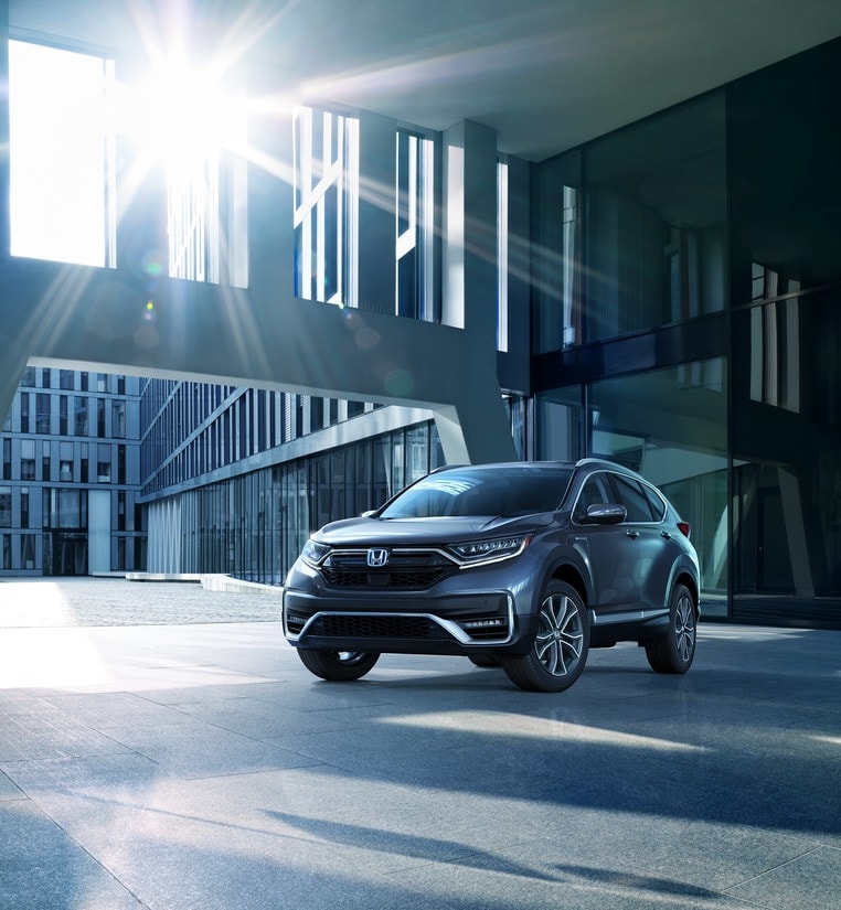 dark gray Honda CR-V SUV parked outside of a modern, glass building