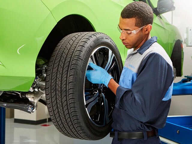 Honda tire rotation at Honda of Salem A Honda technician removing a tire from a vehicle to rotate it.