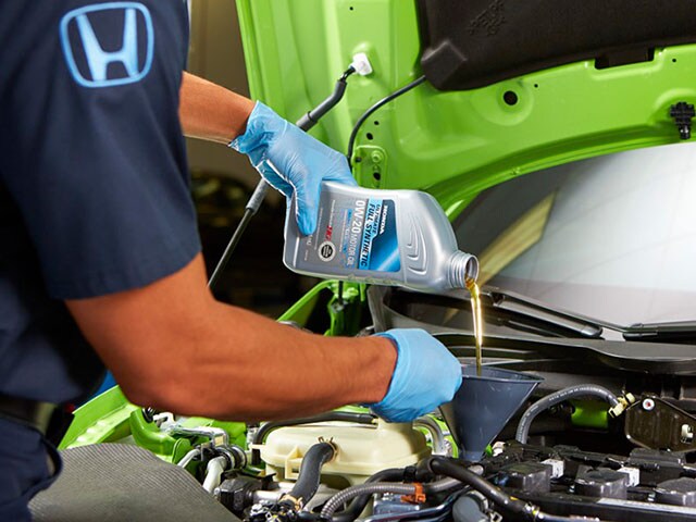 Honda Oil Change at Honda of Salem A Honda service technician pouring oil in to an engine.