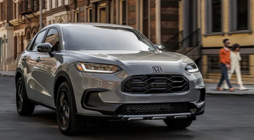 A gray 2025 Honda HR-V Sport is shown driving on a city street.