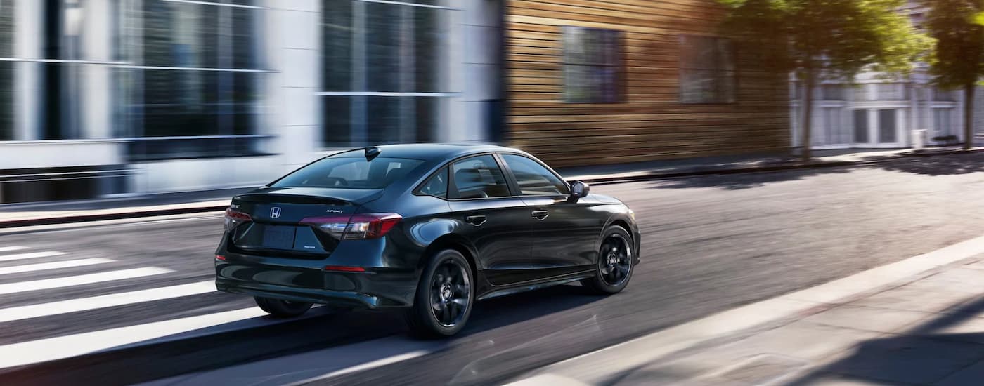 A black 2025 Honda Civic Sport Hybrid is speeding down a city street.