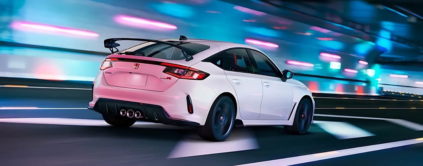 A white 2025 Honda Civic Type R driving under neon lights at night.