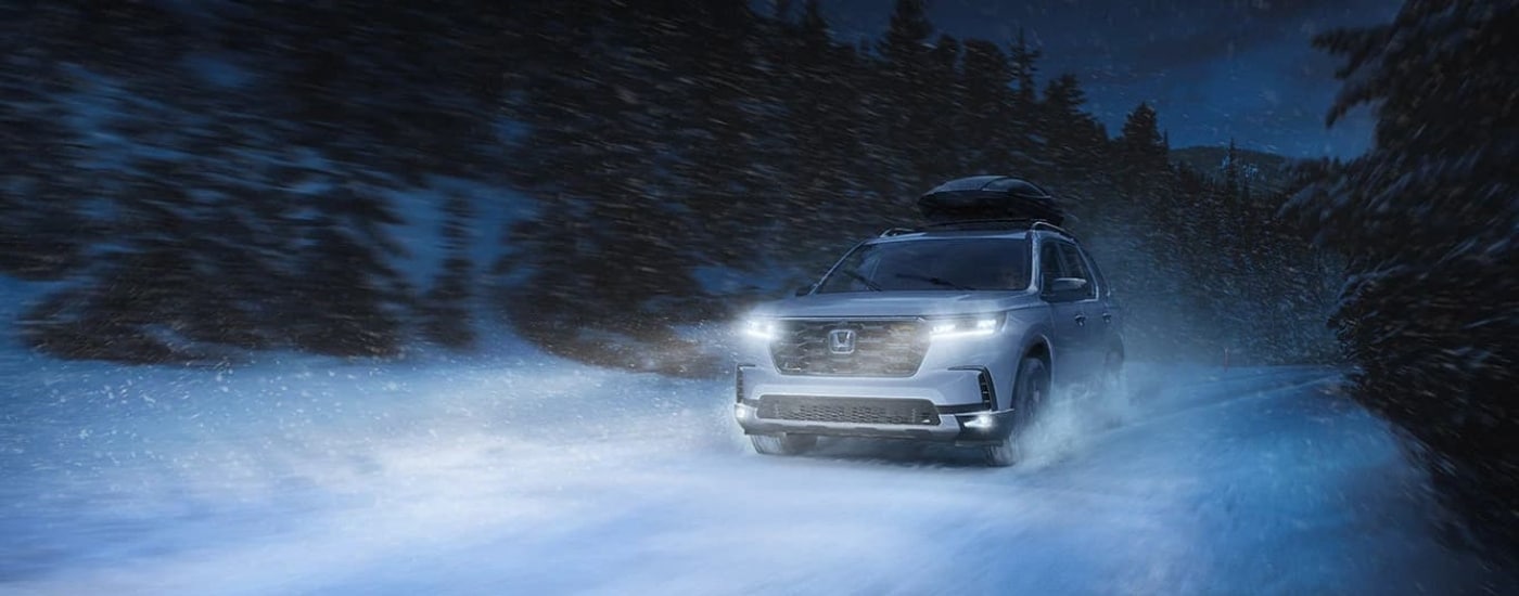 A silver 2023 Honda Pilot TrailSport is shown driving to a used car dealer in Southgate.
