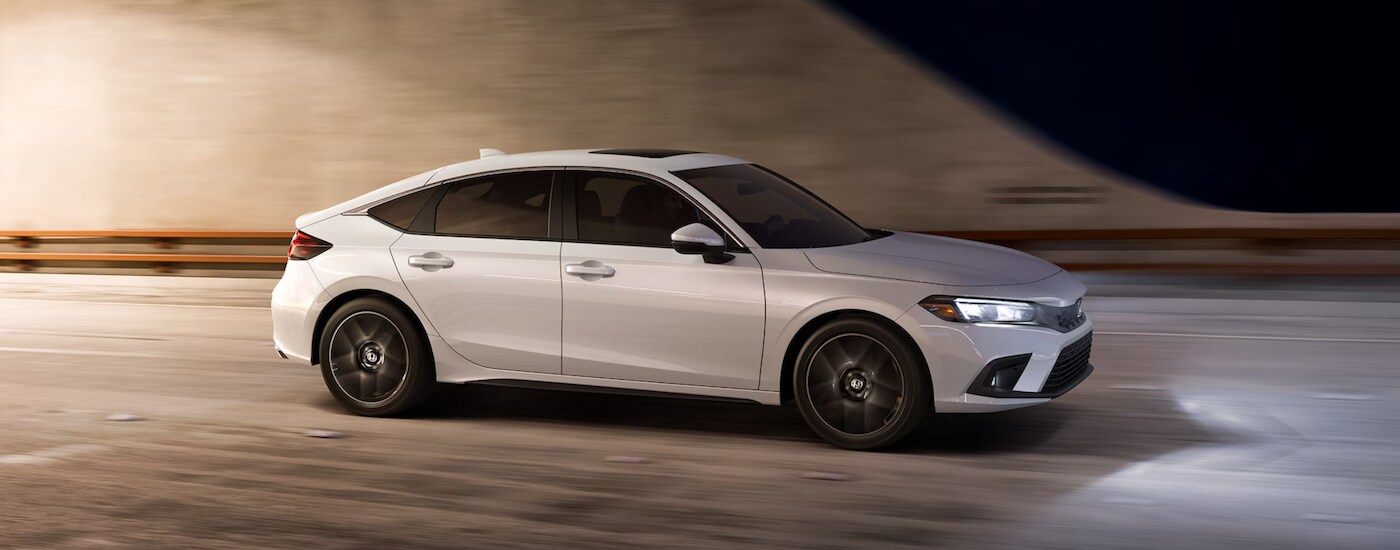 A white 2024 Honda Civic Hatchback Sport Touring driving to a Honda dealer near Dearborn.