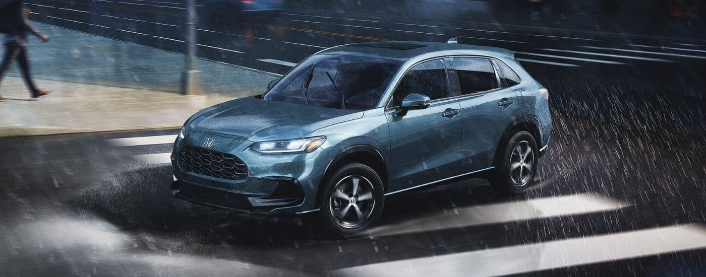 A blue 2026 Honda HR-V driving in a rainy city.