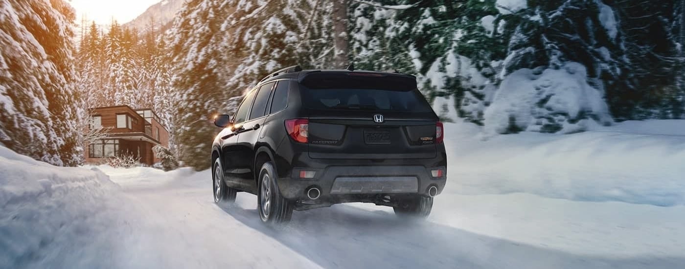 A black 2023 Honda Passport TrailSport is shown driving to a cabin.