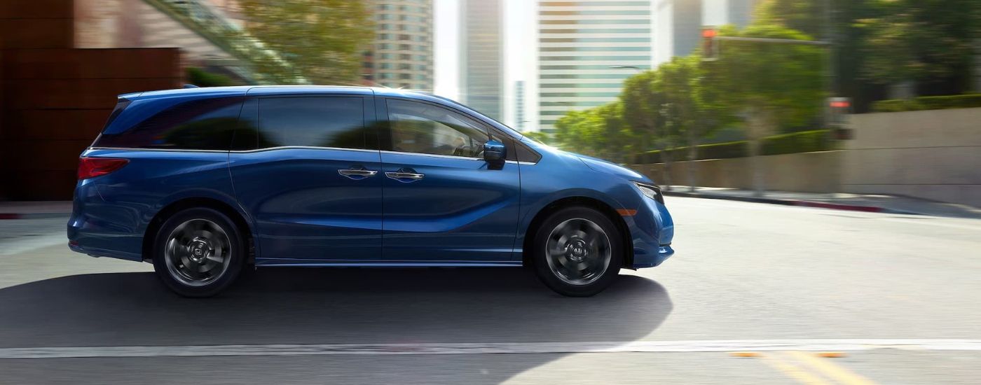 Blue 2024 Honda Odyssey Elite driving through a city