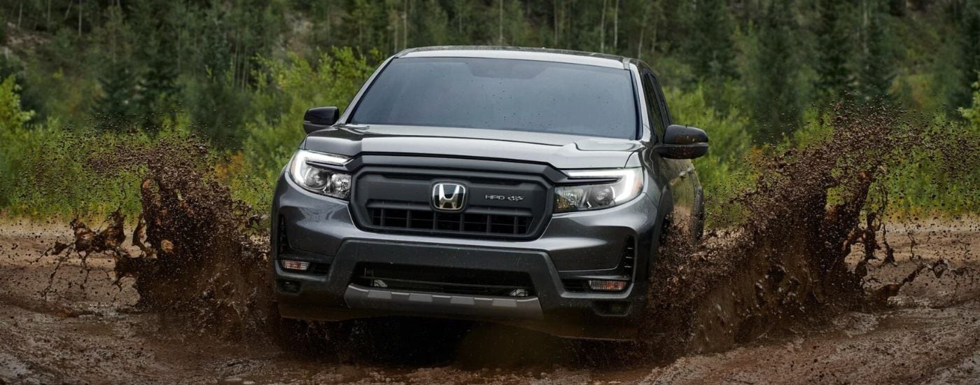 A gray 2024 Honda Ridgeline HPD+ off-roading in mud