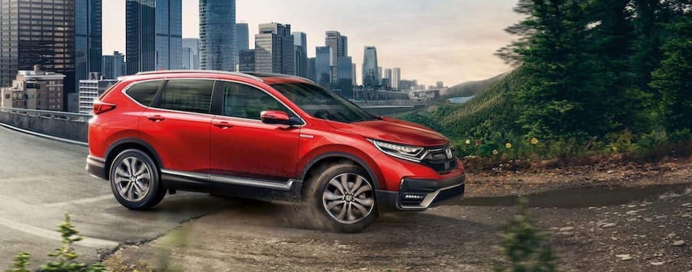 A red 2020 Honda CR-V driving near a city.