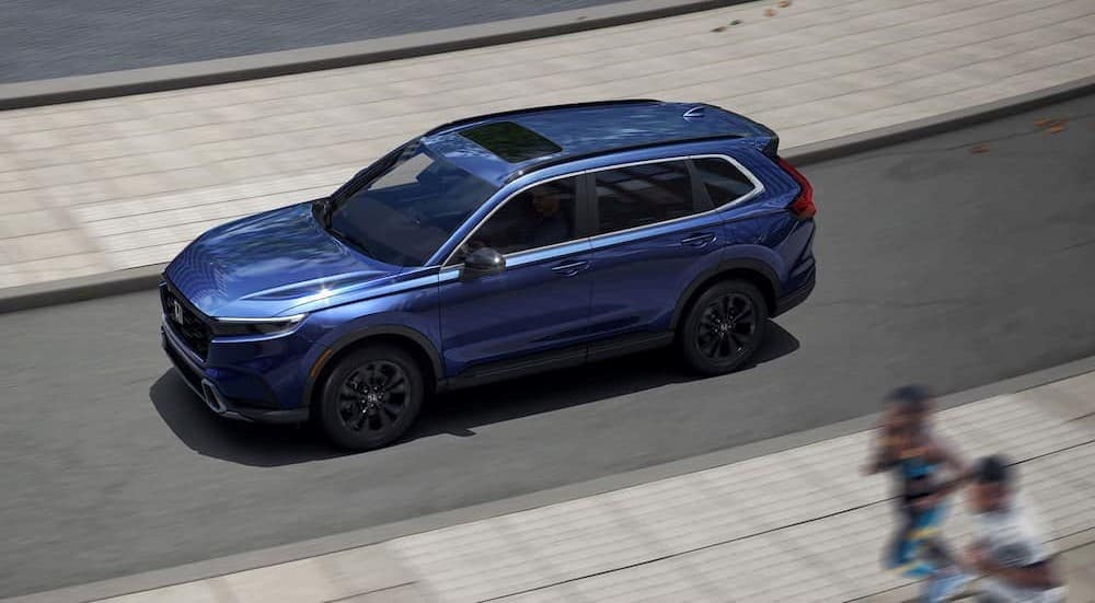 A blue 2025 Honda CR_V driving near joggers.