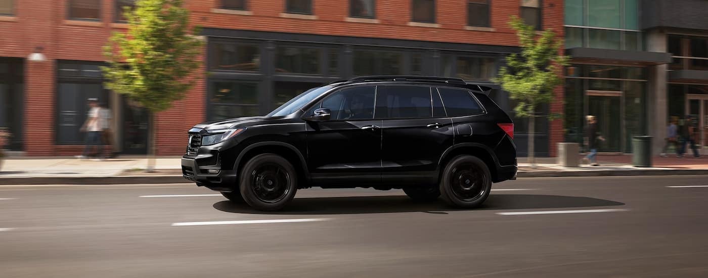 A black 2024 Honda Passport is driving on a city street after leaving a Honda dealer near Canton.