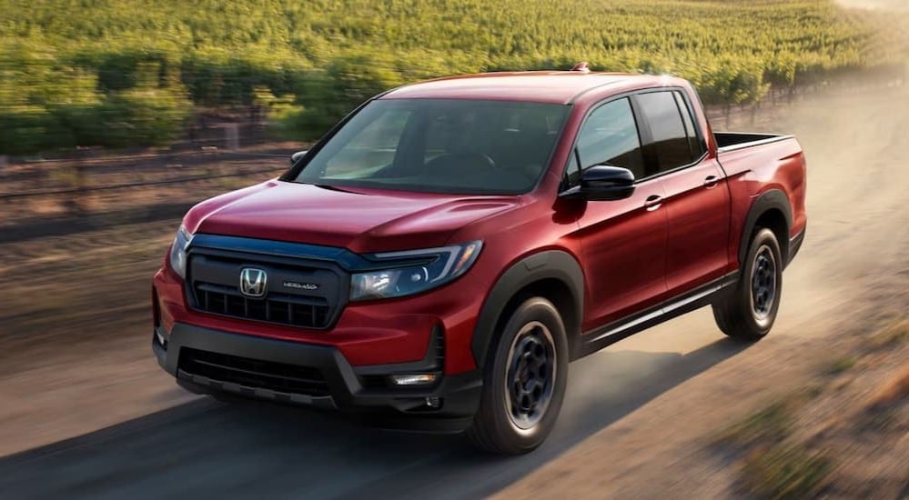 A red 2025 Honda Ridgeline HPD Sport is shown driving on a dirt road.