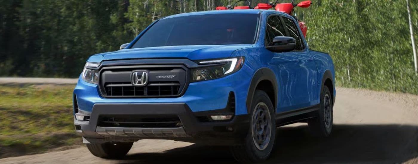 A blue 2025 Honda Ridgeline HPO Trailsport for sale driving on a dirt road.