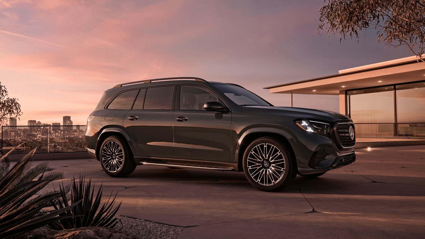 Mercedes-Benz GLS SUV parked in front of a residence with the sun setting in the background