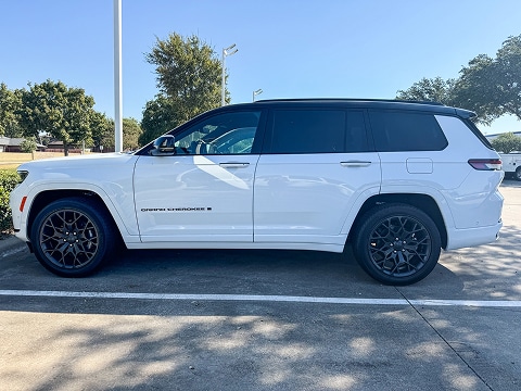 side view of a white 2026 Jeep Grand Cherokee SUV parked at the Huffines CDJR Plano dealership in Plano, TX