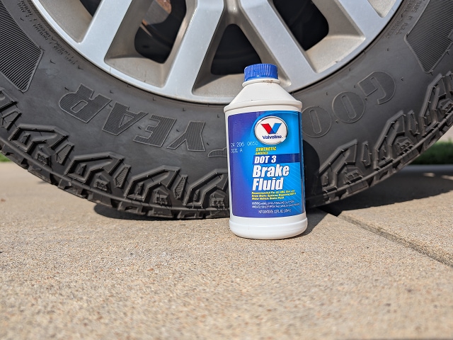 a bottle of brake fluid sitting near a car tire
