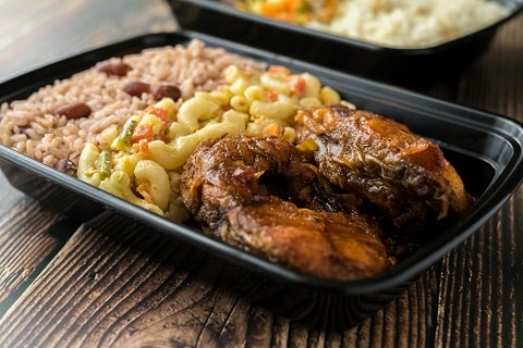 a plate of jerk chicken, red beans and rice, and macaroni salad on a plate at a restaurant in Plano, TX