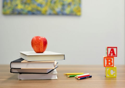 books, an apple, and letter blocks sitting on a desk