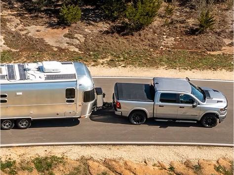 silver 2025 RAM 1500 truck towing a trailer down the road