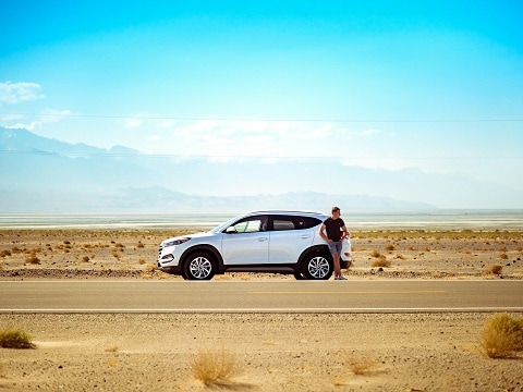 person standing next to car in a desert 