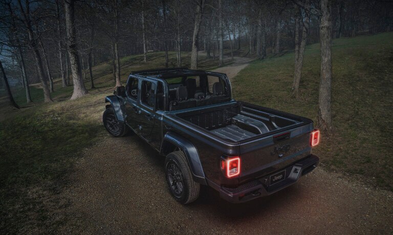 2026 Jeep Gladiator driving away in dark forest