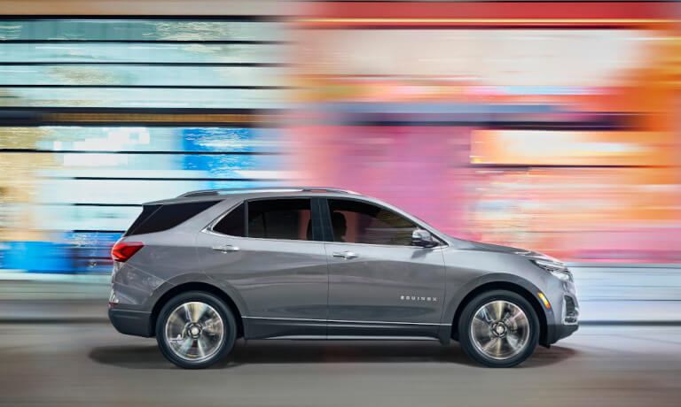 2023 Chevy Equinox driving fast by a colorful building