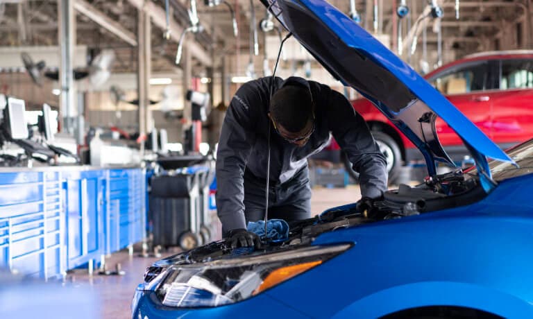 Service technician working under vehicle hood