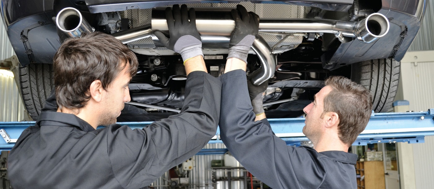 Two technicians working under a car