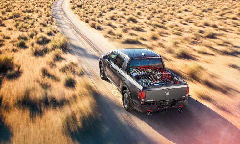 2023 Honda Ridgeline driving in desert with cargo in bed