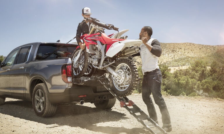 2023 Honda Ridgeline with people loading motorbikes into bed