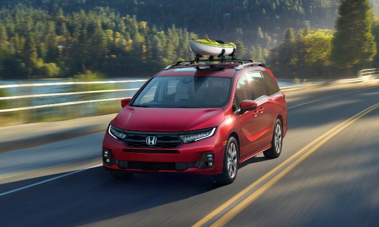 2025 Honda Odyssey driving on highway in forest with kayak
