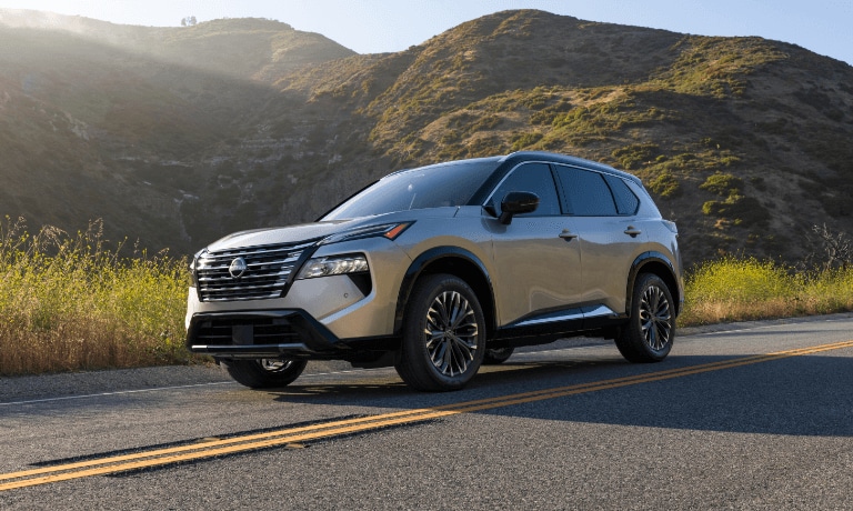 2025 Nissan Rogue driving by grassy hills