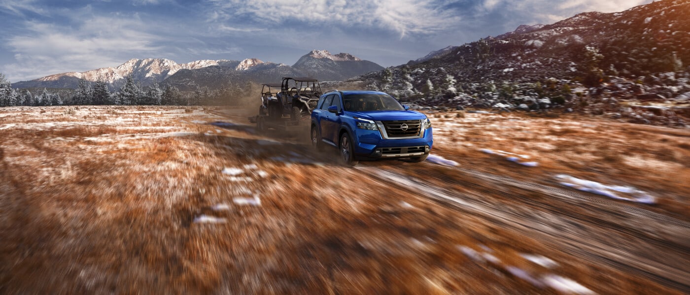 2022 Nissan Pathfinder pulling a trailer in a mountainous field